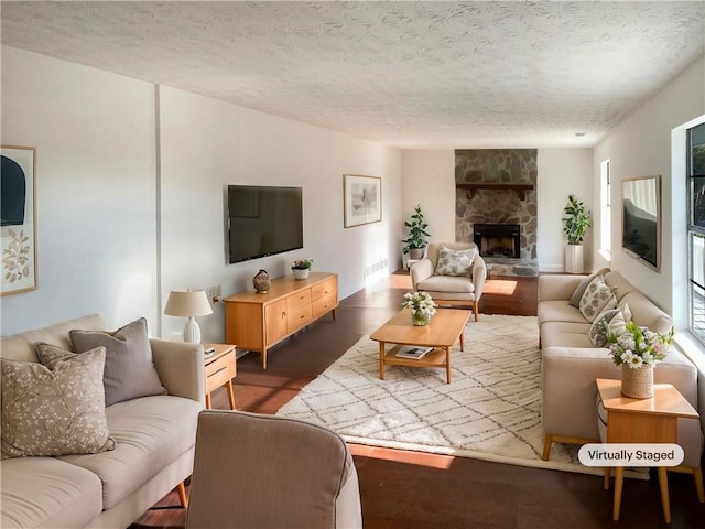 living room featuring a textured ceiling, dark hardwood / wood-style floors, and a stone fireplace