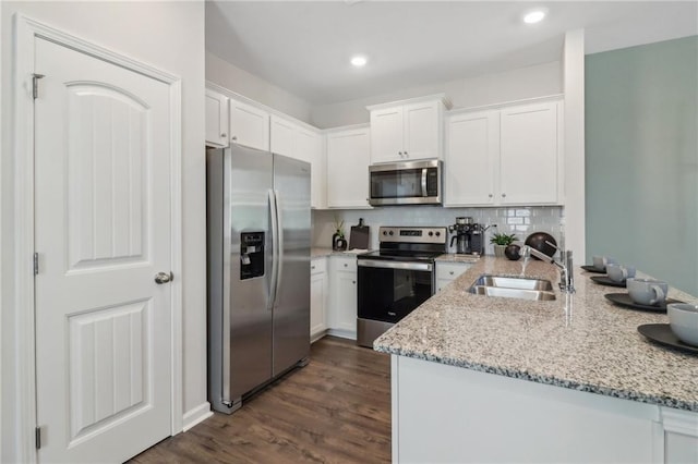 kitchen featuring appliances with stainless steel finishes, sink, backsplash, white cabinetry, and light stone countertops