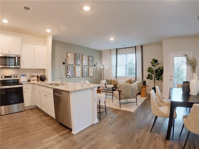 kitchen with sink, appliances with stainless steel finishes, white cabinetry, and a breakfast bar