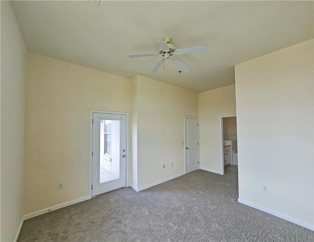 carpeted spare room featuring a ceiling fan and baseboards