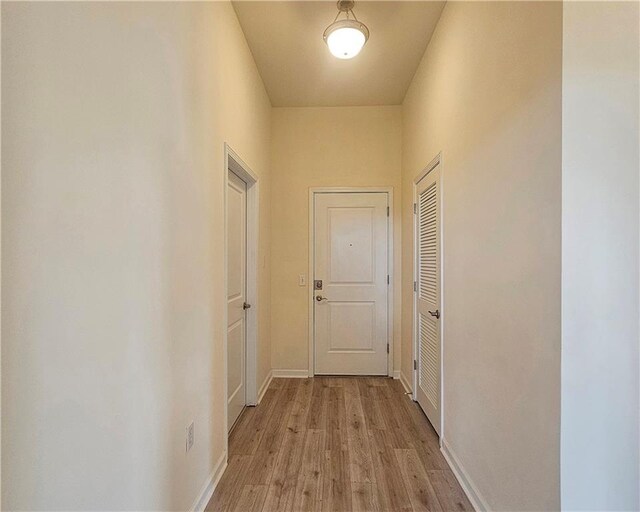 hall featuring light wood-style flooring and baseboards