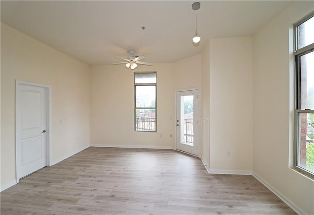 spare room with a ceiling fan, light wood finished floors, and baseboards