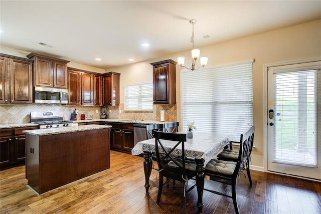 3746 Okefenokee Rdg, Loganville, GA 30052 - kitchen with appliances with stainless steel finishes, dark brown cabinetry, a kitchen island, and recessed lighting