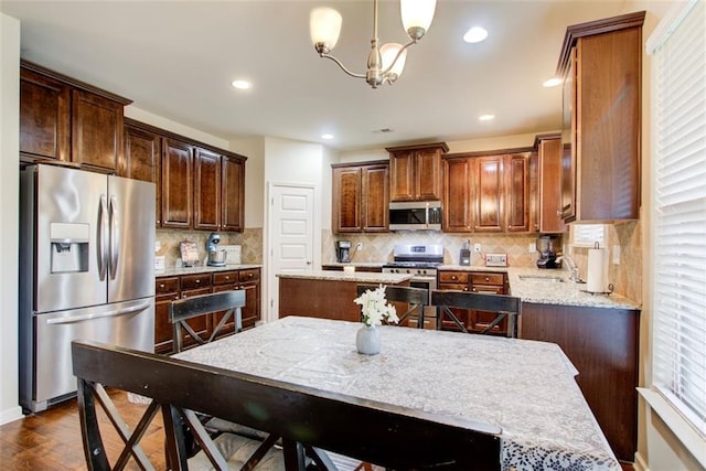 3746 Okefenokee Rdg, Loganville, GA 30052 - kitchen featuring appliances with stainless steel finishes, a sink, decorative backsplash, light stone countertops, and recessed lighting