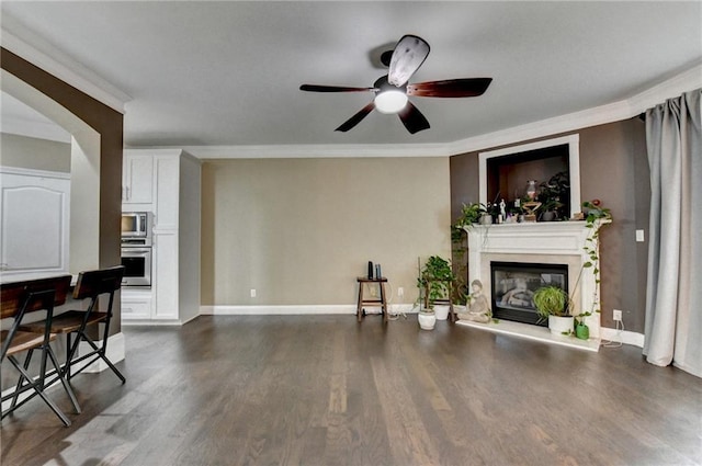 2515 Gadsen Walk, Duluth, GA 30097 - unfurnished living room with crown molding, a glass covered fireplace, ceiling fan, dark wood-type flooring, and arched walkways
