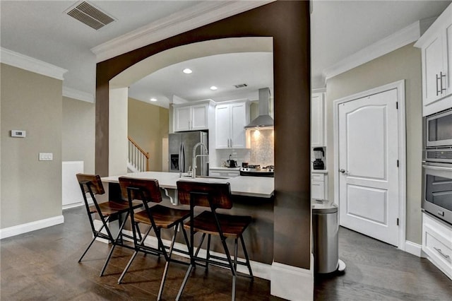 2515 Gadsen Walk, Duluth, GA 30097 - kitchen with wall chimney exhaust hood, stainless steel appliances, a breakfast bar, decorative backsplash, and ornamental molding