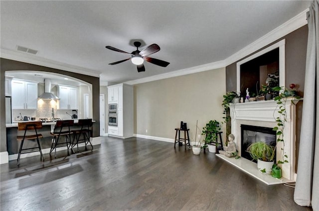 2515 Gadsen Walk, Duluth, GA 30097 - living area featuring ornamental molding, a glass covered fireplace, dark wood-style flooring, a ceiling fan, and arched walkways