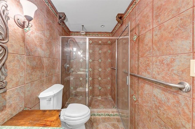 bathroom with a shower with door, tile walls, and toilet