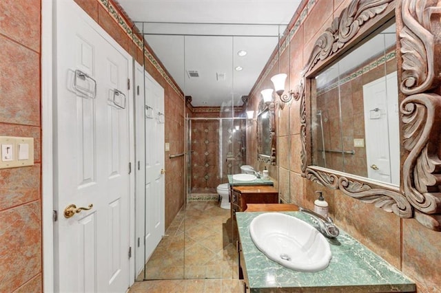 bathroom featuring vanity, toilet, an enclosed shower, and tile walls