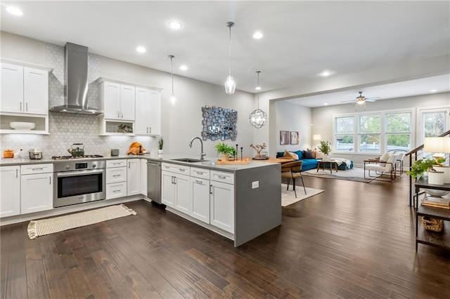 kitchen featuring pendant lighting, white cabinets, wall chimney exhaust hood, and appliances with stainless steel finishes