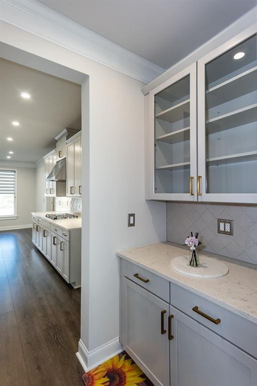 kitchen with crown molding, light stone countertops, and dark hardwood / wood-style floors