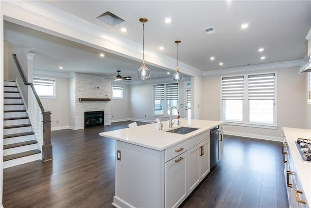 kitchen featuring white cabinetry, hanging light fixtures, crown molding, and a center island with sink