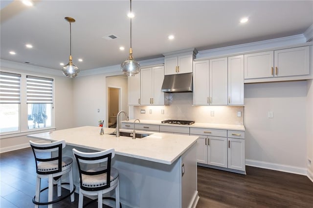 kitchen with sink, white cabinetry, a center island with sink, pendant lighting, and light stone countertops