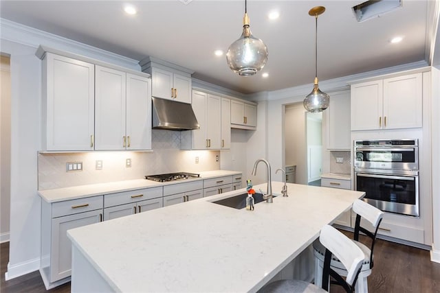 kitchen featuring sink, crown molding, decorative light fixtures, an island with sink, and stainless steel appliances