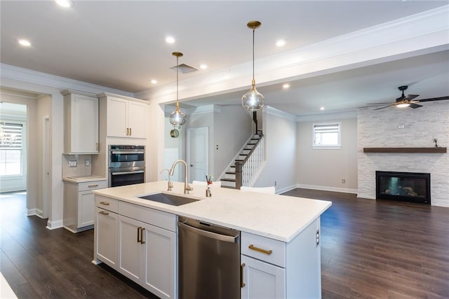 kitchen featuring sink, white cabinetry, decorative light fixtures, appliances with stainless steel finishes, and an island with sink