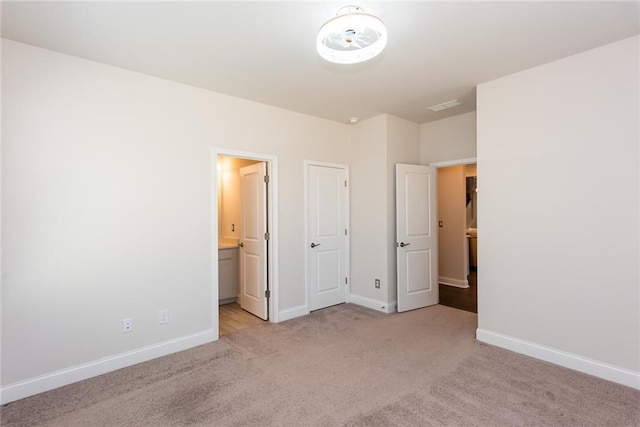 unfurnished bedroom with light carpet and connected bathroom