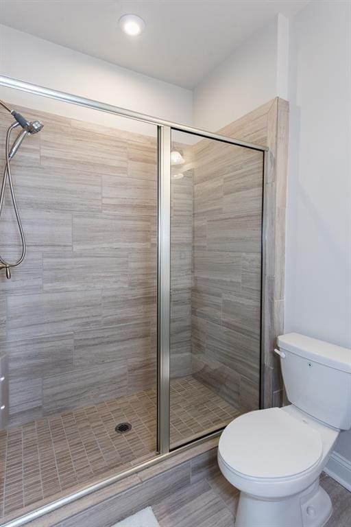 bathroom featuring toilet and a shower with shower door