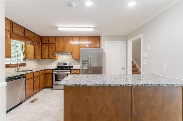 803 Cedar Lake Dr SE, Conyers, GA 30094 - kitchen with stainless steel appliances, a sink, under cabinet range hood, brown cabinets, and ornamental molding