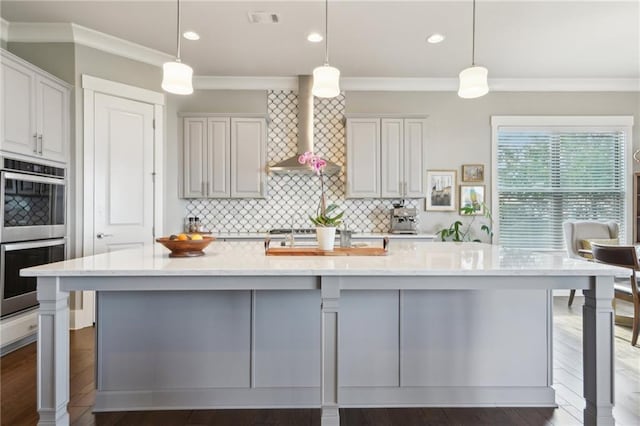 kitchen featuring wall chimney range hood, decorative backsplash, crown molding, and stainless steel double oven