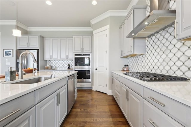 kitchen featuring crown molding, wall chimney range hood, a sink, appliances with stainless steel finishes, and backsplash