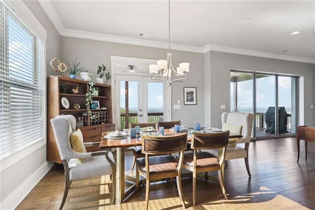dining area with baseboards, ornamental molding, a notable chandelier, and hardwood / wood-style flooring