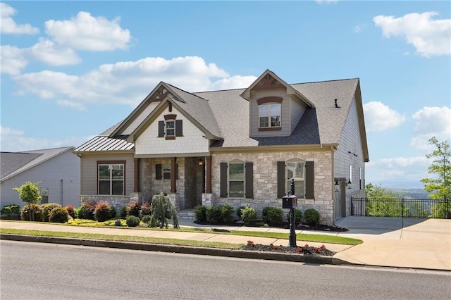 craftsman inspired home with fence, driveway, stone siding, and a garage