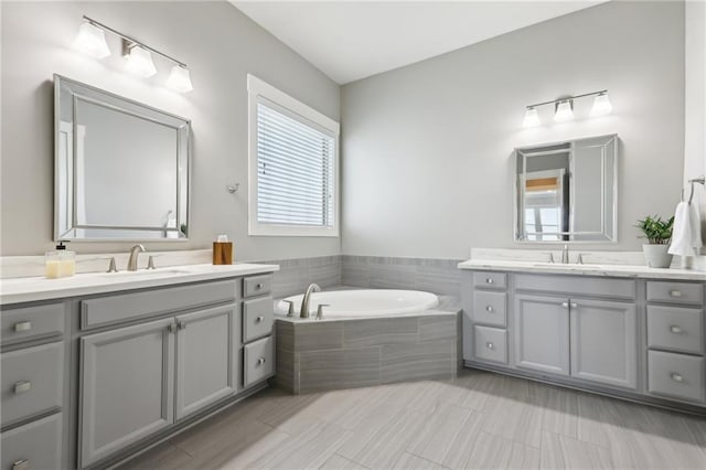 full bathroom featuring a garden tub, a sink, and two vanities