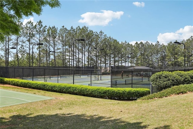 view of sport court with a lawn and fence