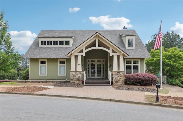 view of front of home with french doors, a shingled roof, a porch, and stone siding