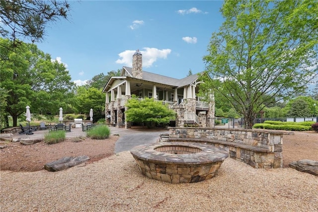 rear view of house with ceiling fan, a chimney, a patio area, stairway, and a fire pit