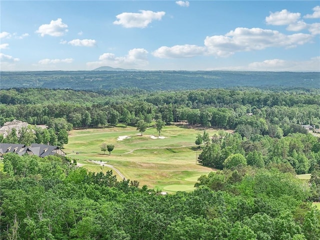 drone / aerial view featuring view of golf course and a wooded view