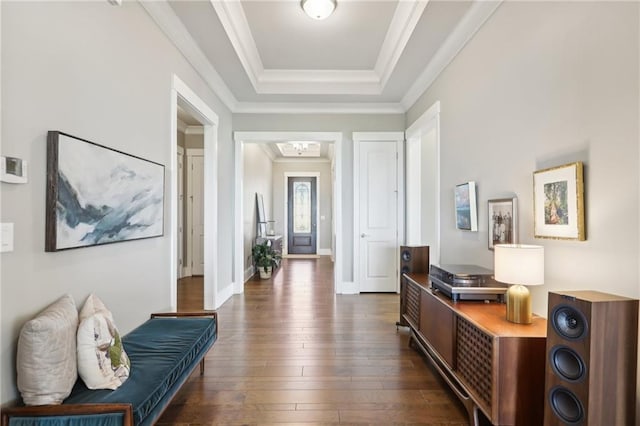 interior space with crown molding, a tray ceiling, baseboards, and dark wood-type flooring