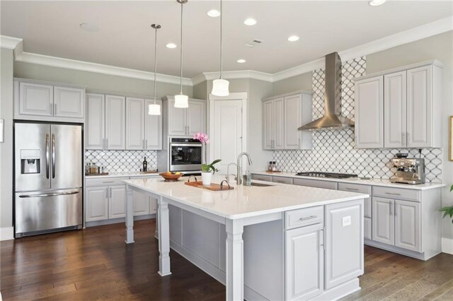 kitchen featuring a sink, ornamental molding, wall chimney range hood, and stainless steel appliances