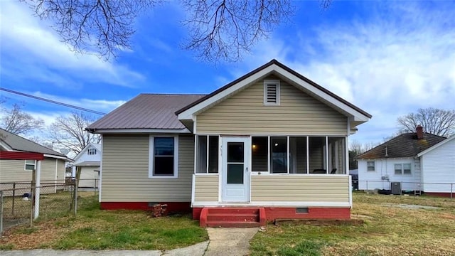 bungalow with a front lawn, entry steps, fence, a sunroom, and metal roof