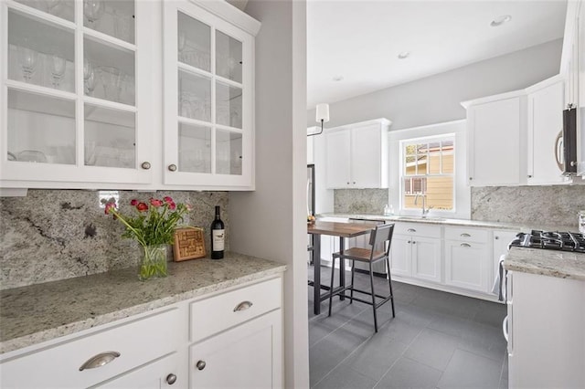 kitchen with light stone countertops, stainless steel microwave, a sink, and white cabinetry