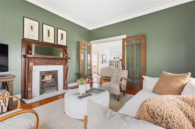 living area featuring ornamental molding, a fireplace, baseboards, and wood finished floors