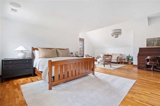 bedroom with visible vents, vaulted ceiling, and wood finished floors