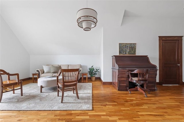 living area with vaulted ceiling, baseboards, and wood finished floors