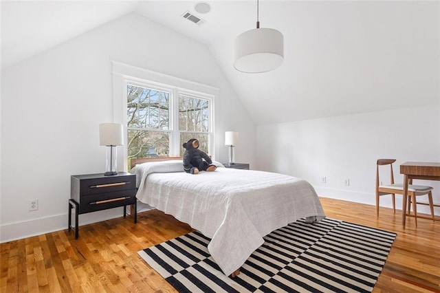 bedroom with lofted ceiling, visible vents, light wood-style flooring, and baseboards