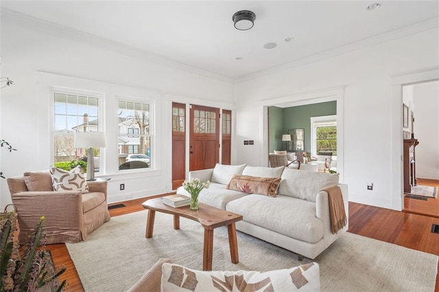 living room featuring baseboards, crown molding, visible vents, and wood finished floors