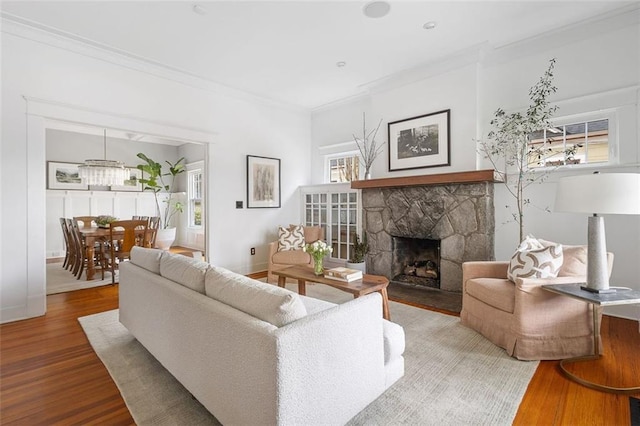 living area featuring ornamental molding, a fireplace, baseboards, and wood finished floors