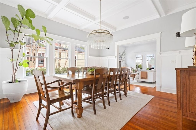 dining area with wood-type flooring, coffered ceiling, a wealth of natural light, and beamed ceiling