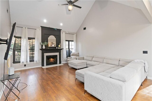 living room featuring ceiling fan, a large fireplace, wood-type flooring, and a wealth of natural light