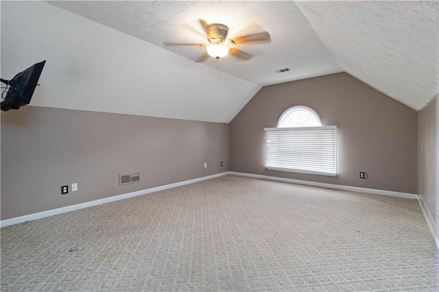 additional living space with carpet, a textured ceiling, and vaulted ceiling