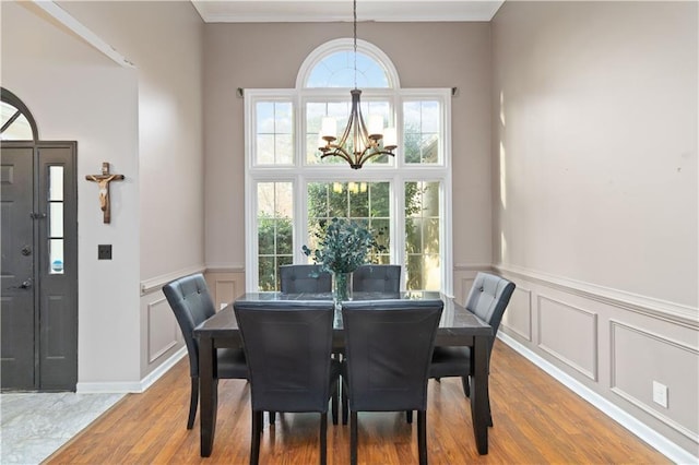 dining area with ornamental molding, wood-type flooring, and an inviting chandelier