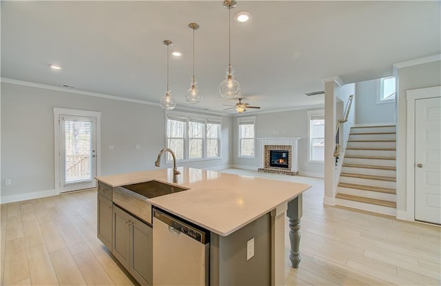 kitchen with a kitchen island with sink, a sink, open floor plan, light countertops, and dishwasher