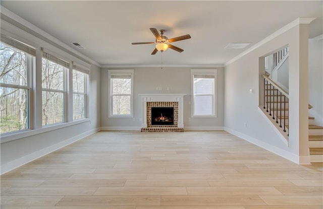 unfurnished living room featuring light wood-type flooring, a wealth of natural light, visible vents, and crown molding