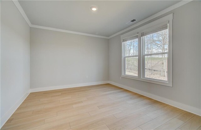 unfurnished room featuring baseboards, light wood finished floors, visible vents, and crown molding