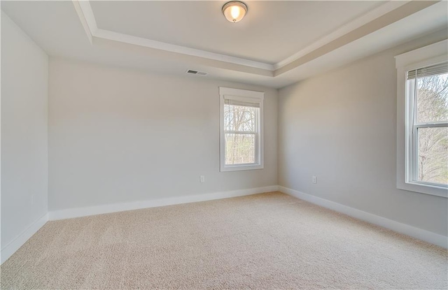 carpeted empty room featuring baseboards, visible vents, and a raised ceiling