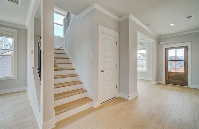 stairs with ornamental molding, visible vents, baseboards, and wood finished floors